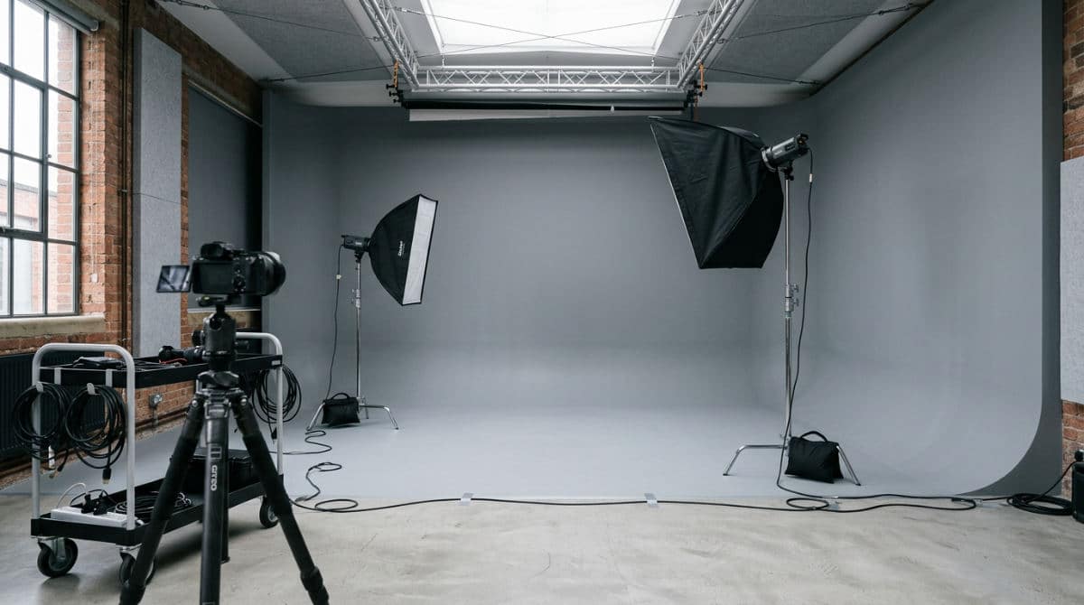 A professional San Diego photography studio featuring a seamless gray cyclorama wall and high-end lighting equipment for headshots.