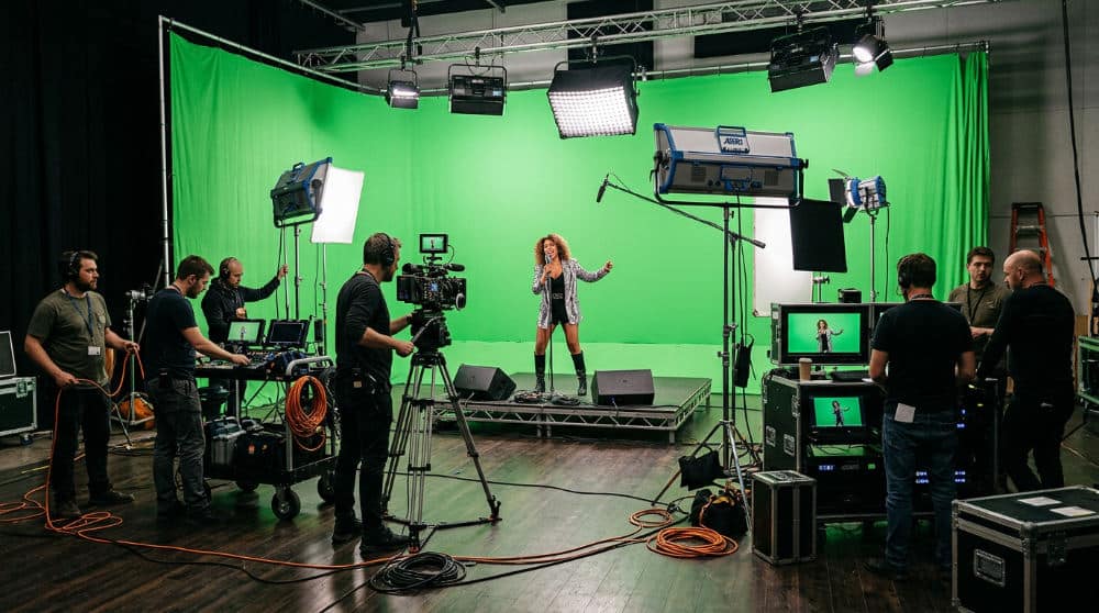 A video production crew filming a music video in a San Diego studio with a green screen.