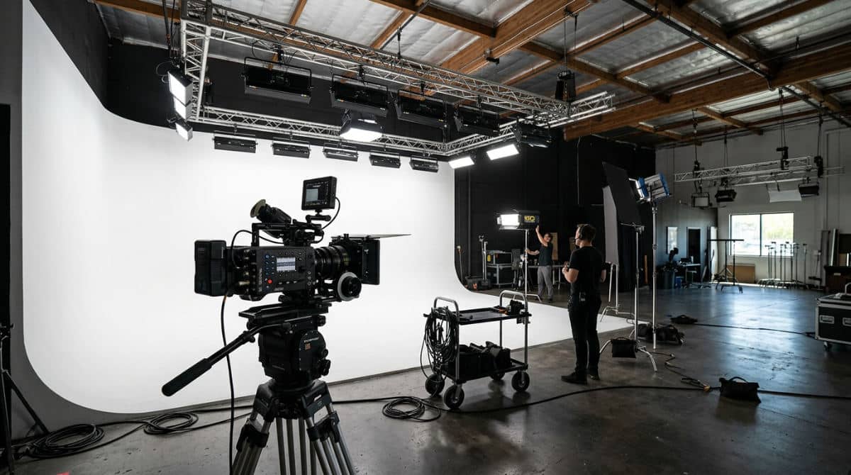A professional San Diego video studio featuring a clean white cyclorama wall and ceiling-mounted lighting rigs for production.