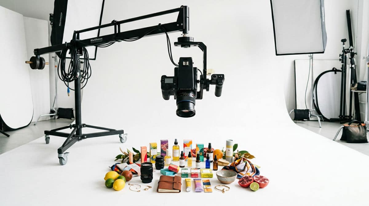 A professional camera rigged on a boom arm for birds eye photography over a white cyclorama wall.