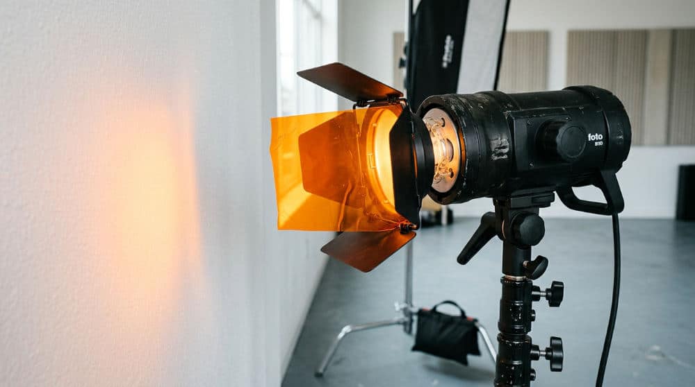 A studio strobe with an orange gel being used to create colored lighting in a studio.