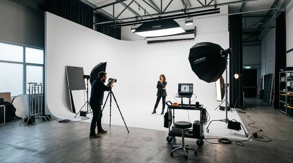 A professional photography studio interior featuring a large white cyclorama wall used for high-quality headshots.
