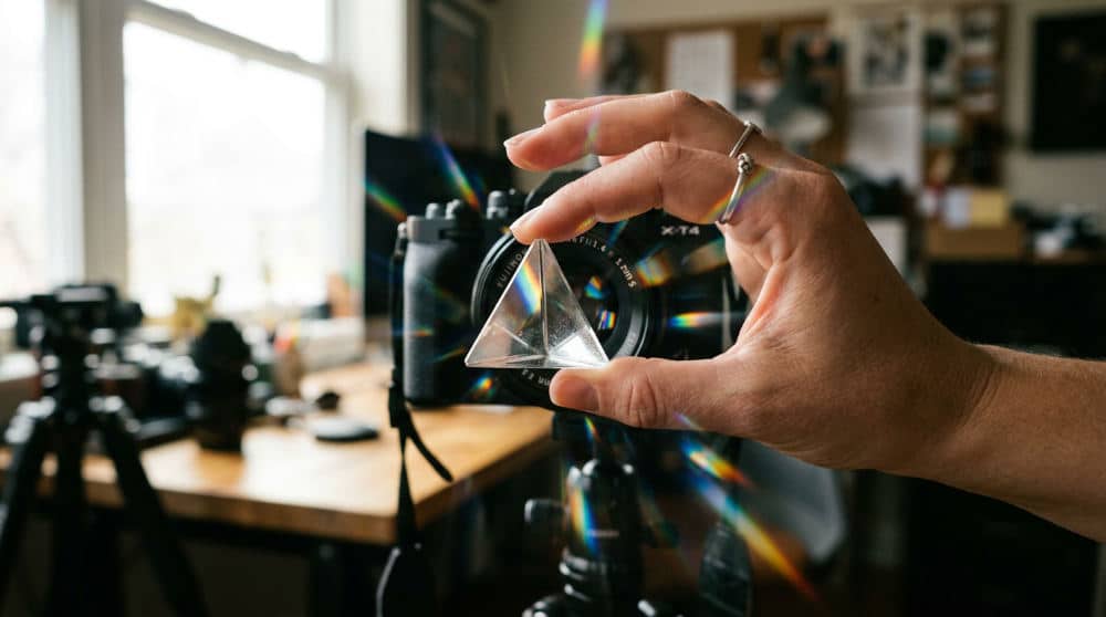 Photographer using a glass prism to refract light and create double vision effects.