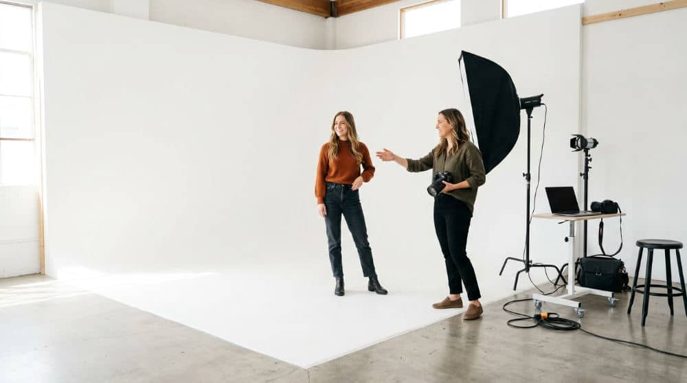 A photography coach guiding a realtor through professional poses in a San Diego studio.