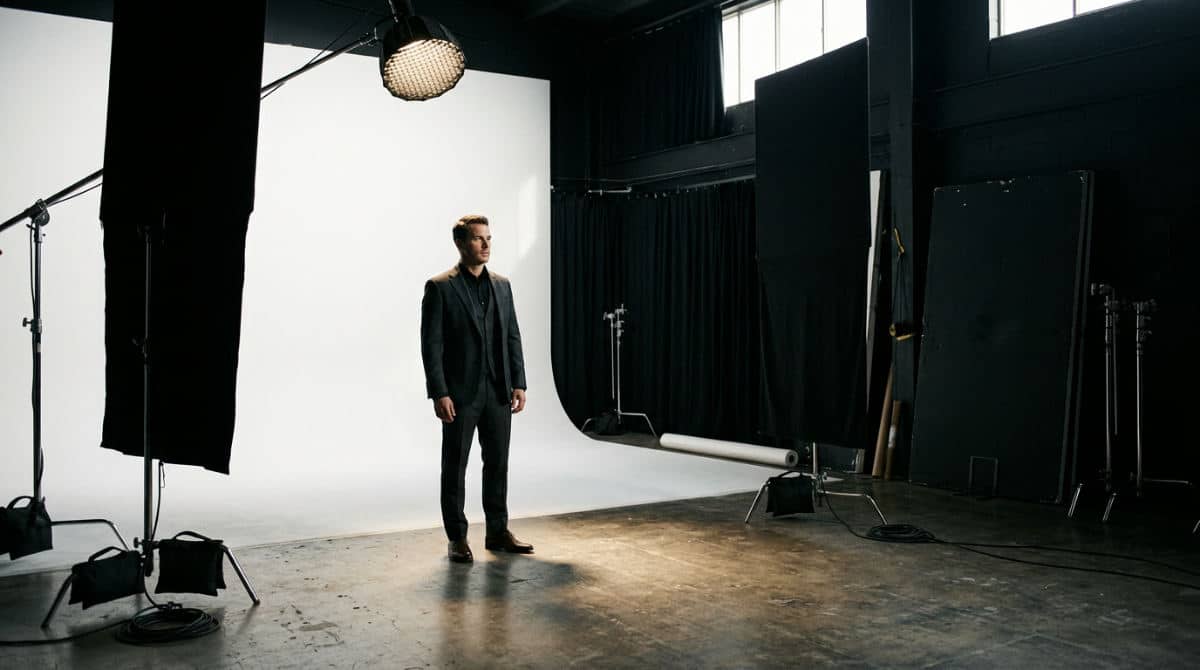 A professional photography studio with a cyclorama wall set up for a high-contrast portrait session using negative fill.