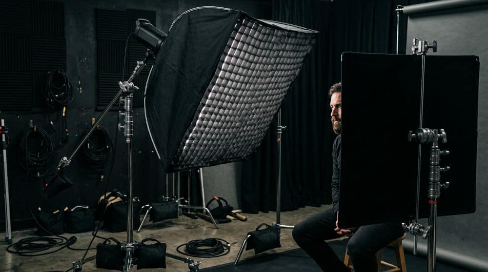 Detailed view of studio lighting equipment including a grid and black flag for high contrast effects.