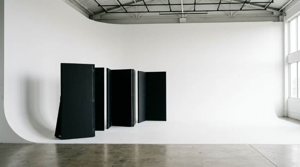 A clean white cyclorama wall in a professional photography studio equipped with black V-flats for light control.