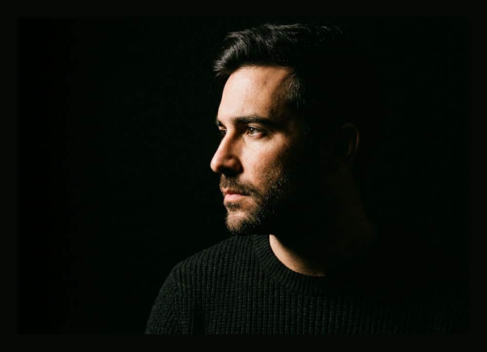 A dramatic silhouette of a subject against a deep black background created using professional studio light flags.