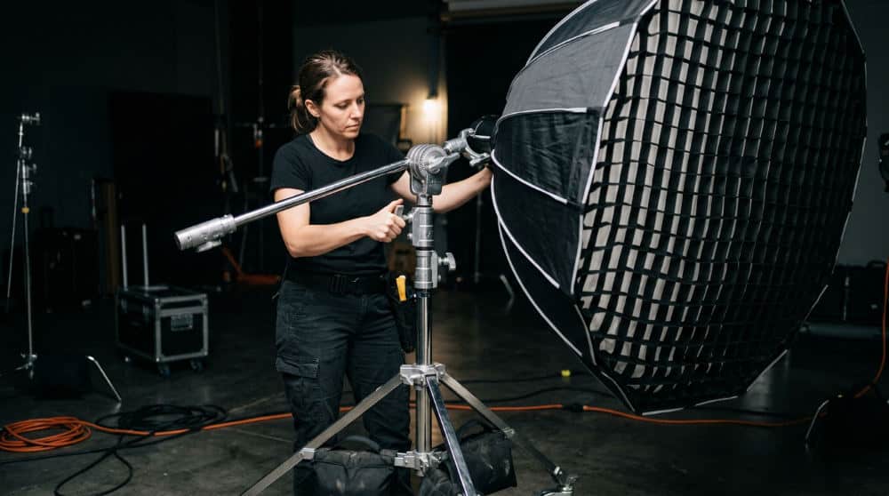 A technician adjusting a professional octabox modifier on a C-stand during a photo studio equipment rental session.