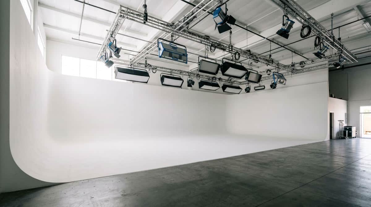 A professional photography studio in San Diego featuring a large white cyclorama wall and ceiling-mounted lighting equipment.