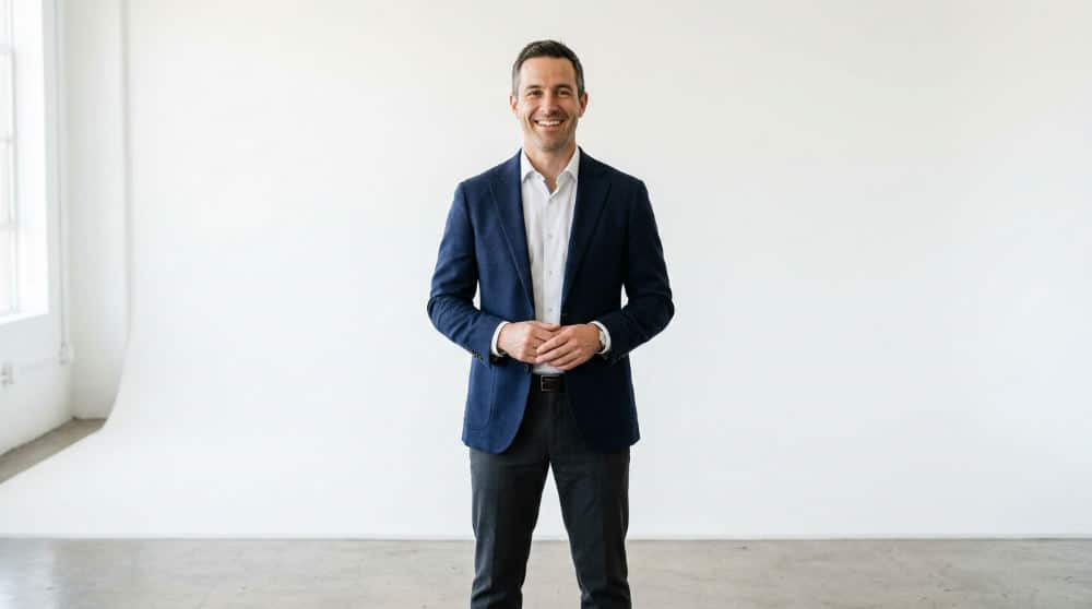 A man in a suit posing for pro photo headshots against a clean studio background.