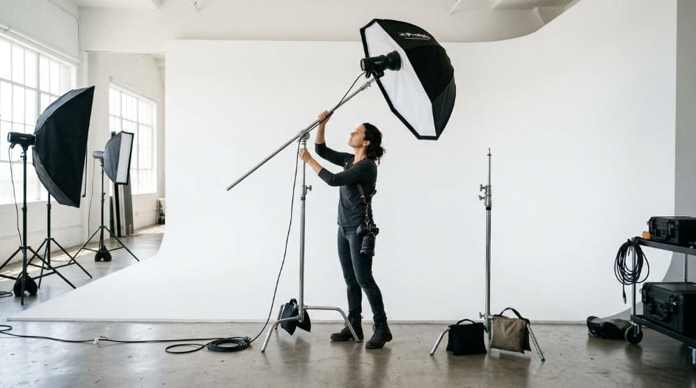 A photographer setting up premium lighting in a San Diego studio for a professional business headshot session.