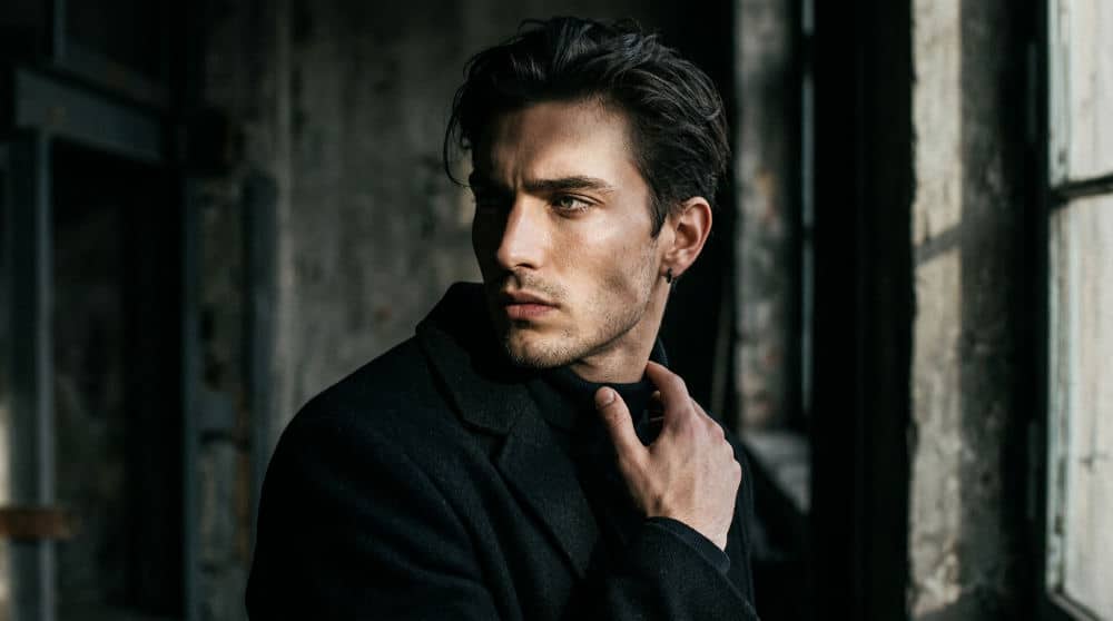 A male model showcasing an editorial headshot with dramatic lighting and an intense facial expression.